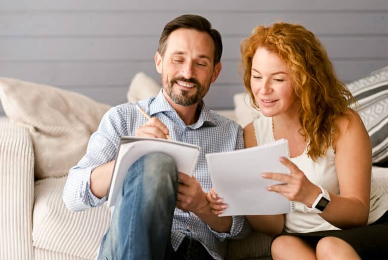 A marketing team, consisting of a man and woman from Gen X, analyzing statistics on a piece of paper while sitting on a couch.
