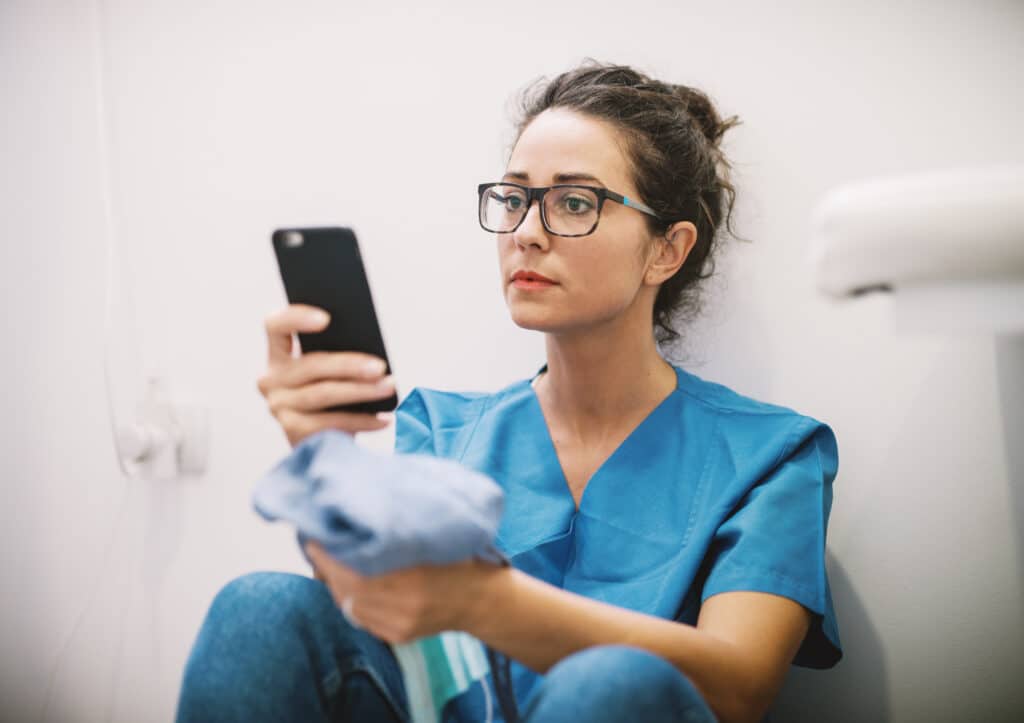 A nurse discreetly checking social media on her phone during a short break.